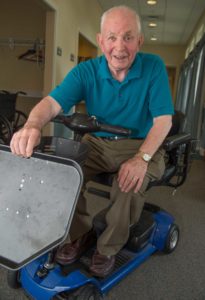 John Staehlin of Carroll Lutheran Village demonstrates a modified “scooter” cart with adjustable food tray which he invented for a friend. The tray device allows his friend to move through a cafeteria line on his scooter as he receives food.